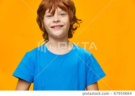 Little boy beautiful smile blue t-shirt yellow background red hair 67950664