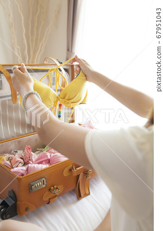 A woman taking out a swimsuit from a suitcase A woman taking out a swimsuit from a suitcase 67951043