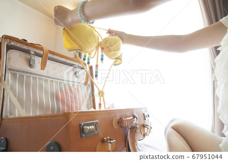 A woman taking out a swimsuit from a suitcase A woman taking out a swimsuit from a suitcase 67951044