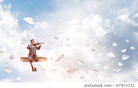 Handsome violinist play his melody and paper planes fly around Handsome violinist play his melody and paper planes fly around 67953252