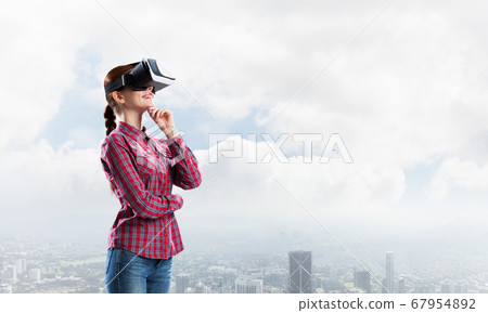 Girl in checked shirt wearing VR glasses experiencing another reality Girl in checked shirt wearing VR glasses experiencing another reality 67954892