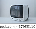 A white 14" color crt television on a white desk and wall in oblique angle 67955110