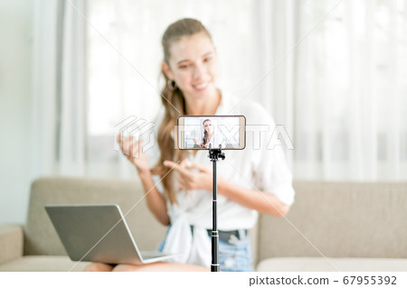 Beautiful woman with white shirt show and live review the cosmetic product in front the camera Beautiful woman with white shirt show and live review the cosmetic product in front the camera 67955392