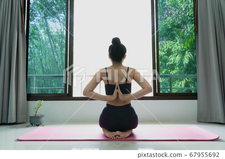fitness, people and healthy lifestyle concept -woman wearing sportswear practicing yoga with namaste behind the back, sitting in seiza exercise, vajrasana pose, working out at home,rear view 67955692
