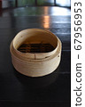 A Cylindrical wooden basket for adding dim sum on dark brown table 67956953