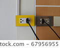 Yellow and dark silver power outlets on white and wood wall 67956955