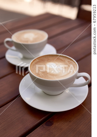Two cups of cappuccino on the wooden background Two cups of cappuccino on the wooden background 67959213
