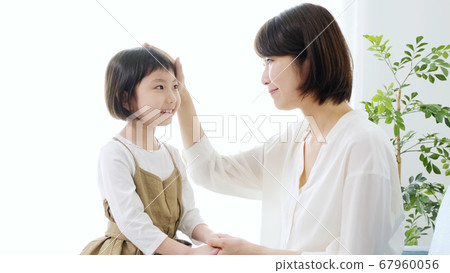 Mother stroking daughter's head 67960056