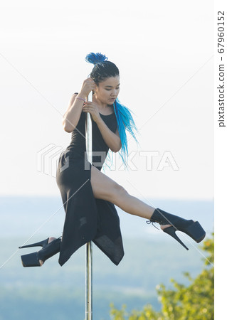 Woman with blue braids on high heels dancing pole dance Woman with blue braids on high heels dancing pole dance 67960152