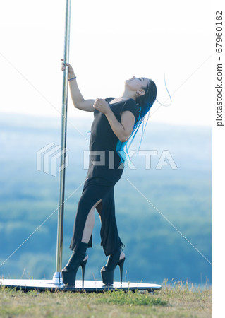 Woman with blue braids on high heels holding by the pole and leaning back Woman with blue braids on high heels holding by the pole and leaning back 67960182
