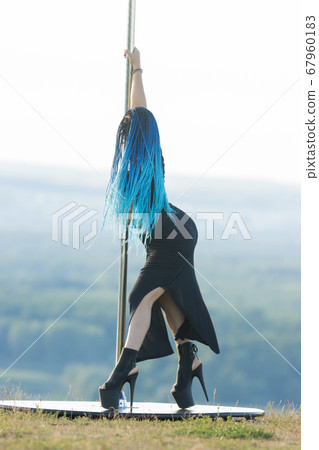 Woman with blue braids on high heels holding by the pole outdoors Woman with blue braids on high heels holding by the pole outdoors 67960183