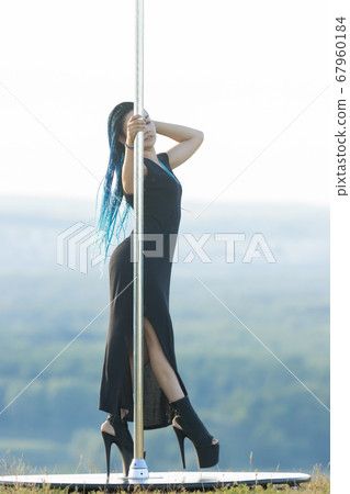 Woman with blue braids standing by the pole outdoors Woman with blue braids standing by the pole outdoors 67960184