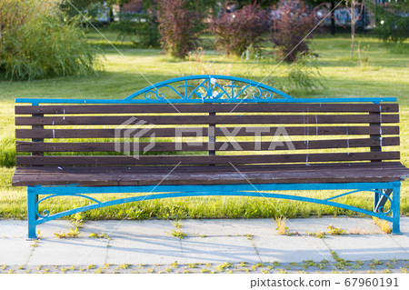 An emptY brown and blue bench in the summer park An emptY brown and blue bench in the summer park 67960191