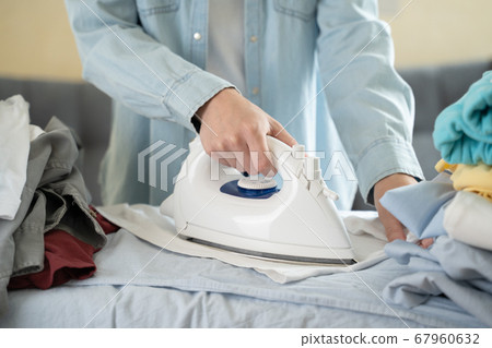 Happy woman ironing her clothes at home Happy woman ironing her clothes at home 67960632
