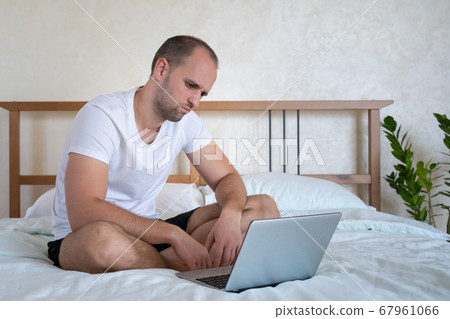 Financial losses for a man working on a laptop on a bed in the bedroom 67961066