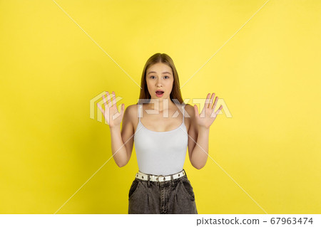 Caucasian young girl's portrait isolated on yellow studio background. Beautiful female model. Concept of human emotions, facial expression, sales, ad, youth culture. Caucasian young girl's portrait isolated on yellow studio background. Beautiful female model. Concept of human emotions, facial expression, sales, ad, youth culture. 67963474