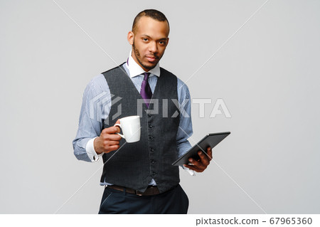 professional african-american business man holding tablet pc and cup of coffee 67965360