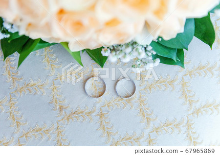Beautiful wedding rings lie on light surface Beautiful wedding rings lie on light surface 67965869