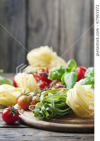 Raw pasta, tomato and basil on the wooden table Raw pasta, tomato and basil on the wooden table 67965972