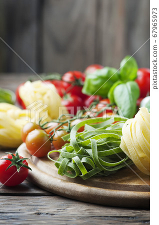 Raw pasta, tomato and basil on the wooden table 67965973