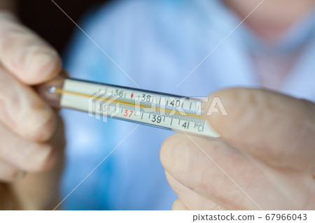 Hands holding medical thermometer. Hands holding medical thermometer. 67966043