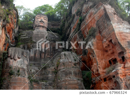 The Leshan Giant Buddha or Leshan Grand Buddha near Chengdu, Sichuan, China. The Leshan giant is the tallest stone Buddha statue in the world. View from a boat on the river near to Leshan and Chengdu. The Leshan Giant Buddha or Leshan Grand Buddha near Chengdu, Sichuan, China. The Leshan giant is the tallest stone Buddha statue in the world. View from a boat on the river near to Leshan and Chengdu. 67966324
