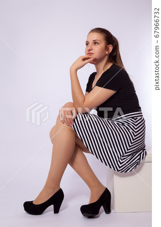 A young girl is sitting on a stool 67966732