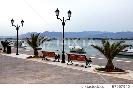 The harborside with fishing boats floating in the pretty harbor in Nafplio. Nafplio is an old town in Peloponnese Greece with historic roots. Nafplio is also known as Nafplion, Nauplio and Nauplion. The harborside with fishing boats floating in the pretty harbor in Nafplio. Nafplio is an old town in Peloponnese Greece with historic roots. Nafplio is also known as Nafplion, Nauplio and Nauplion. 67967940