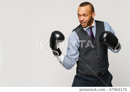 Angry upset young man office worker, business employee, fists in air with boxing gloves, open mouth yelling and shouting, negative emotion facial expression feeling Angry upset young man office worker, business employee, fists in air with boxing gloves, open mouth yelling and shouting, negative emotion facial expression feeling 67968178