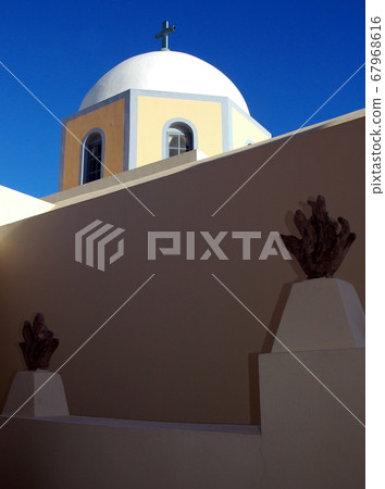 St John the Baptist Cathedral is a Roman Catholic church in Fira (Thira), Santorini, Greece. It is one of many churches in Fira, Santorini. The church has a white dome against a blue sky. Santorini. 67968616