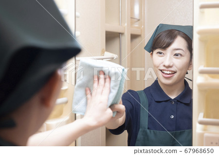 Female worker in house cleaning wiping mirror in washroom 67968650