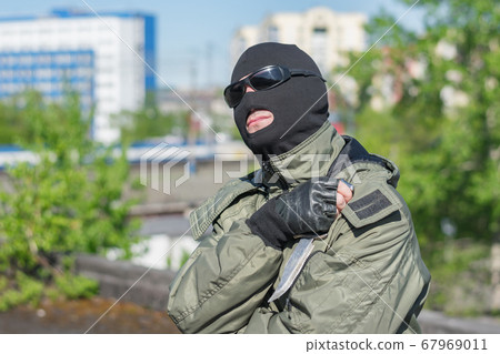 A bandit in a mask and black glasses rests and looks at the sun A bandit in a mask and black glasses rests and looks at the sun 67969011