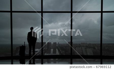 The man with suitcase standing near the big windows in the business center The man with suitcase standing near the big windows in the business center 67969112