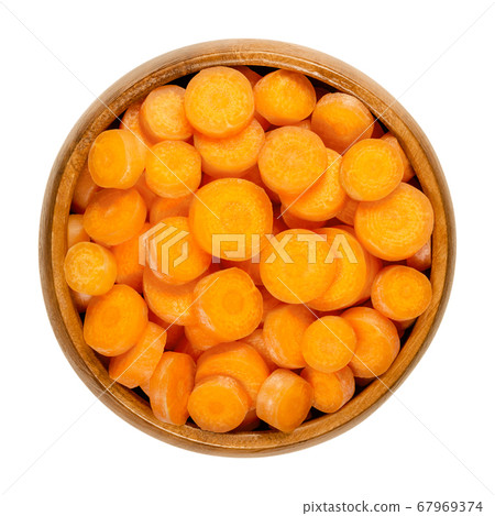 Small carrot slices in wooden bowl. Crunchy and fresh, unpeeled, small and young carrots, cut into round discs, ready-to-eat and as a snack. Close-up from above, over white, isolated macro food photo. Small carrot slices in wooden bowl. Crunchy and fresh, unpeeled, small and young carrots, cut into round discs, ready-to-eat and as a snack. Close-up from above, over white, isolated macro food photo. 67969374