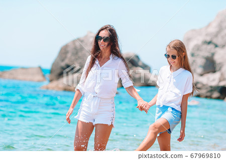 Beautiful mother and daughter on the beach enjoying summer vacation Beautiful mother and daughter on the beach enjoying summer vacation 67969810