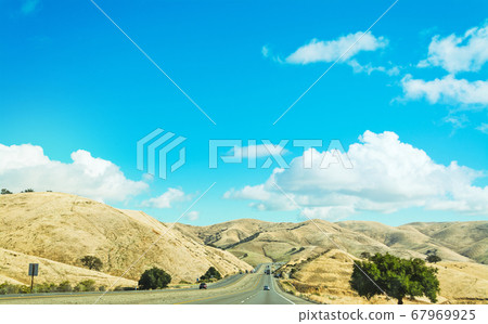 country road surrounded by hills in California 67969925