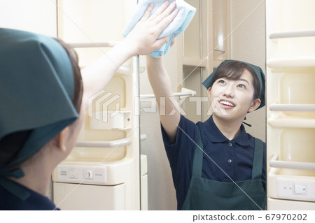 女工在房子清潔擦鏡子在洗手間 女工在房子清潔擦鏡子在洗手間 67970202
