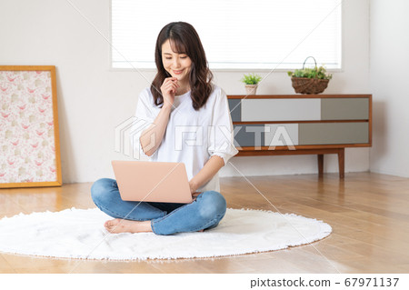 Young woman cross-legged in living room and looking at laptop 67971137