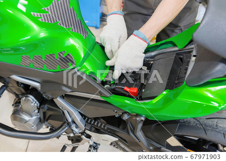 The master performs maintenance on the motorcycle. 67971903