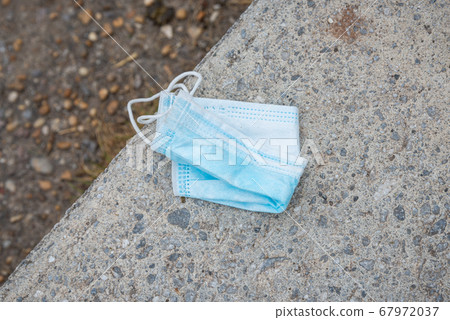 Disposable face mask discarded on concrete floor 67972037