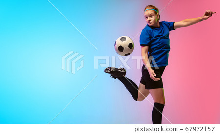 Female soccer, football player training in action isolated on gradient studio background in neon light Female soccer, football player training in action isolated on gradient studio background in neon light 67972157
