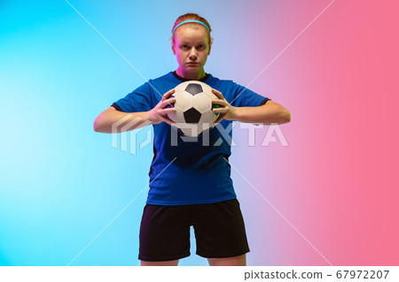 Female soccer, football player training in action isolated on gradient studio background in neon light Female soccer, football player training in action isolated on gradient studio background in neon light 67972207