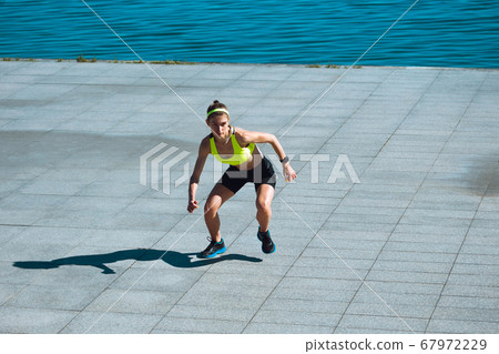 Female runner, athlete training outdoors in summer's sunny day. Female runner, athlete training outdoors in summer's sunny day. 67972229