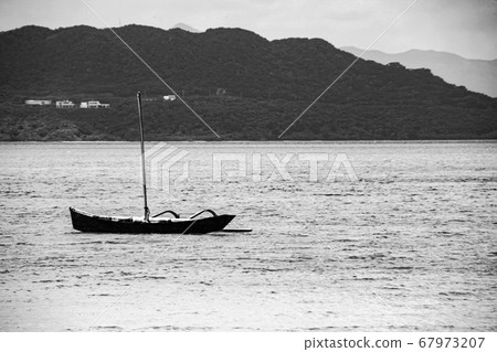 沖繩海洋中漂浮的一艘小船的黑白照片 67973207