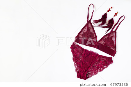 Sexy lace burgundy women's lingerie with fashion earrings isolated on white background. Top view with copy space 67973386