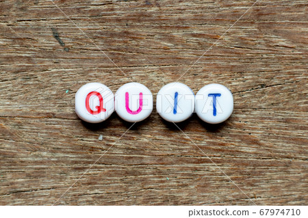 White bead with color letter in word quit on wood background White bead with color letter in word quit on wood background 67974710