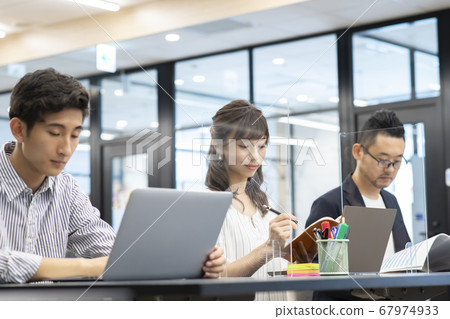 Men and women who work on computers in seats separated by partitions to prevent splashing 67974933