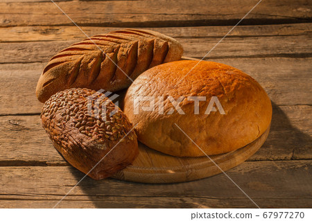 Three loaves of homemade bread on cutting board. 67977270