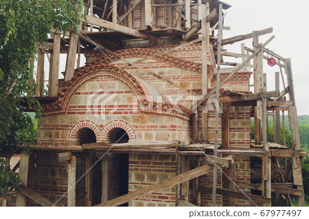Construction of a new church in a modern style. Scaffolding around the white walls of the church. New project. 67977497