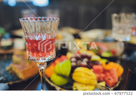 Focus on hands serving dishes of meat and vegetables to a group of friends gathered around a table on a summer terrace. 67977522